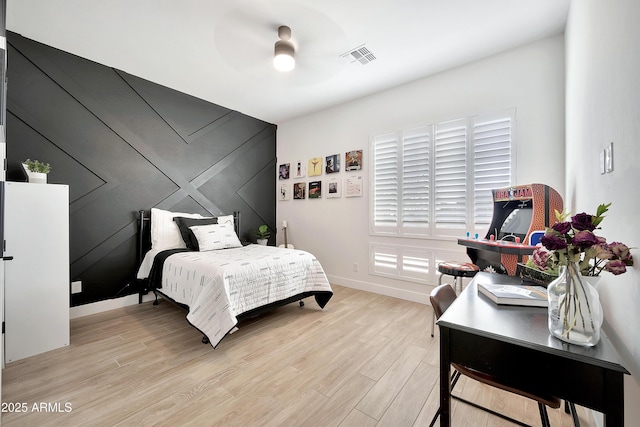 bedroom with a ceiling fan, light wood-type flooring, visible vents, and baseboards