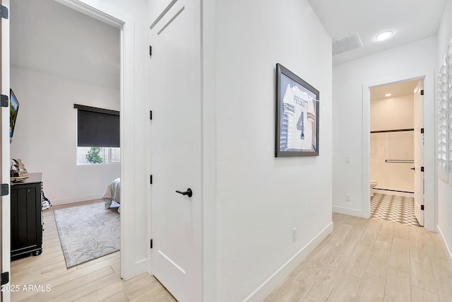 hall featuring light wood finished floors, visible vents, and baseboards