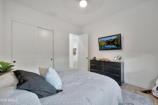 bedroom featuring baseboards, visible vents, ceiling fan, light wood-type flooring, and a closet