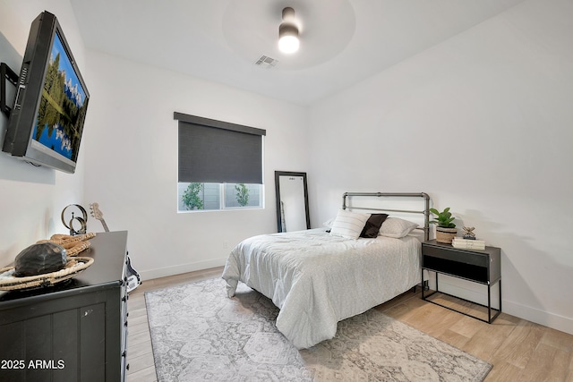 bedroom featuring a ceiling fan, wood finished floors, visible vents, and baseboards