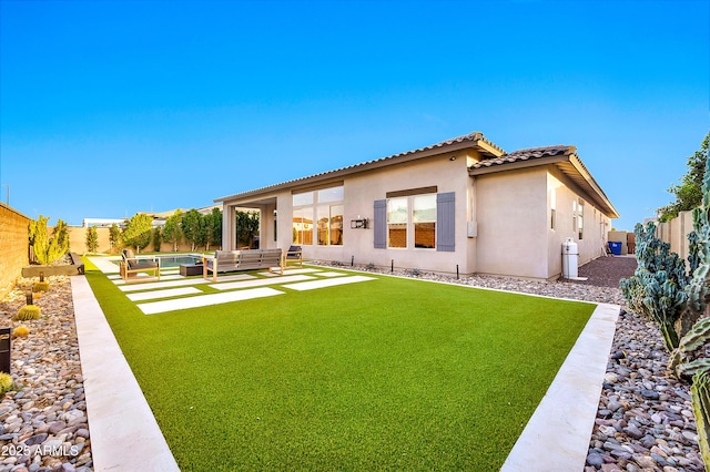 back of property with a fenced backyard, an outdoor living space, a yard, a tiled roof, and stucco siding