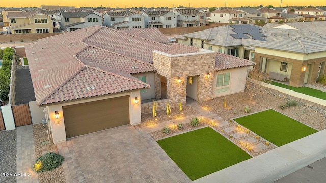 view of front facade featuring fence, a garage, a residential view, stone siding, and a tiled roof