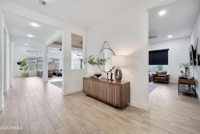 corridor featuring light wood-type flooring, visible vents, baseboards, and recessed lighting