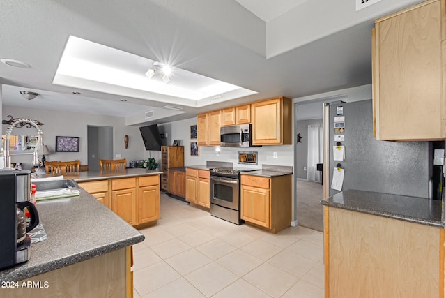 kitchen with kitchen peninsula, light brown cabinetry, light tile patterned flooring, and stainless steel appliances