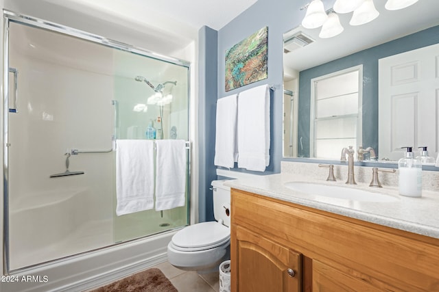 bathroom featuring a shower with shower door, vanity, tile patterned flooring, and toilet