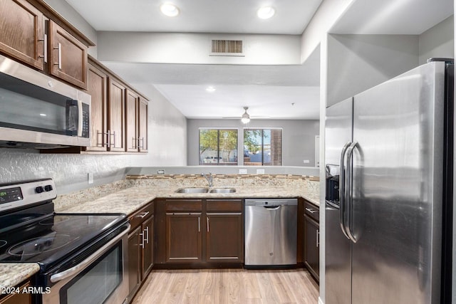 kitchen with ceiling fan, sink, kitchen peninsula, appliances with stainless steel finishes, and light wood-type flooring