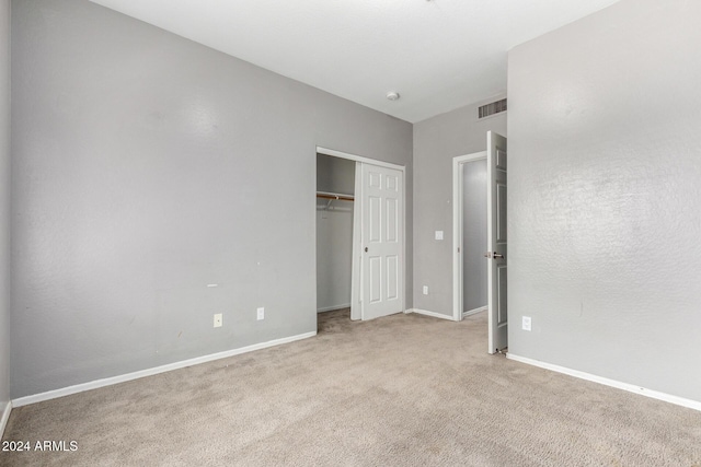 unfurnished bedroom with light carpet and a closet