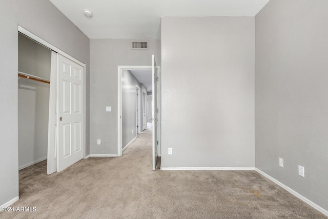 unfurnished bedroom featuring light colored carpet and a closet