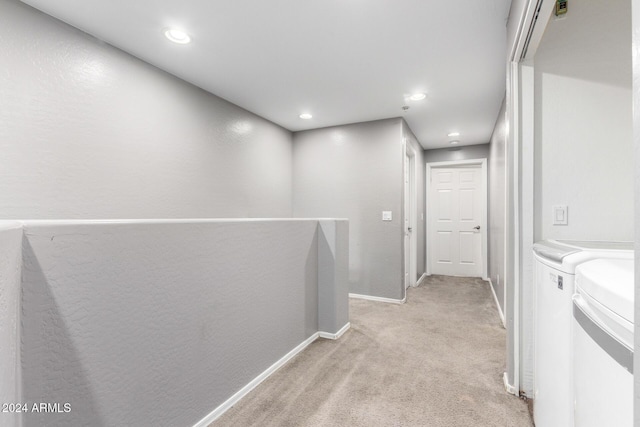 hallway with light carpet and washing machine and clothes dryer