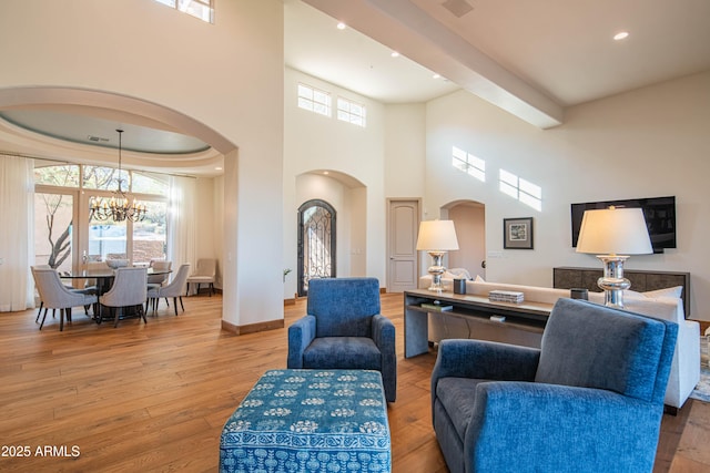 living room featuring a towering ceiling, light hardwood / wood-style floors, and a chandelier