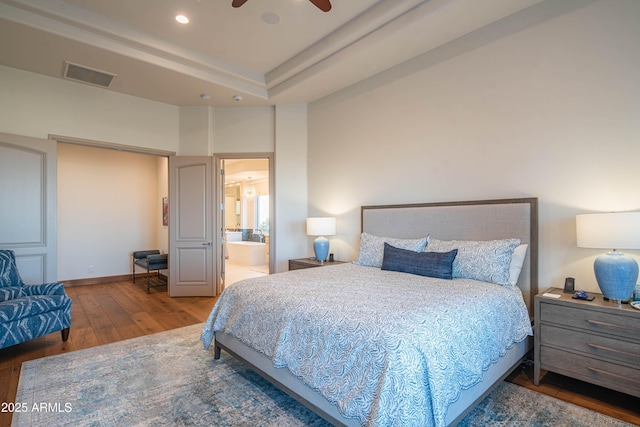 bedroom with hardwood / wood-style floors and ensuite bath