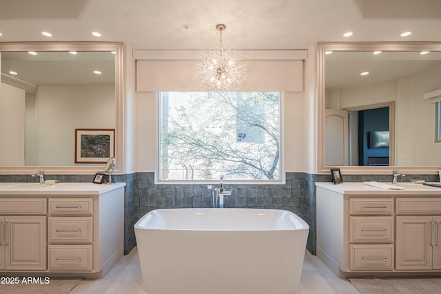 bathroom featuring vanity, tile walls, a chandelier, and a tub to relax in