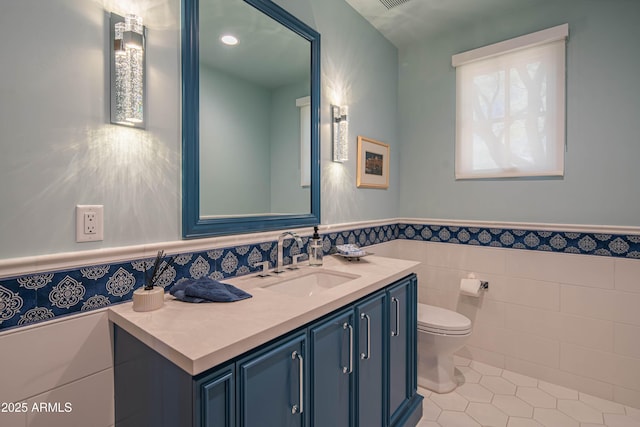 bathroom featuring vanity, tile patterned floors, tile walls, and toilet