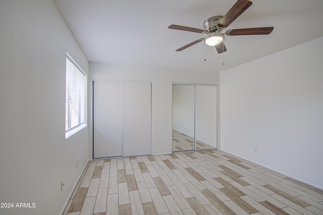 unfurnished bedroom with ceiling fan, light hardwood / wood-style floors, and two closets