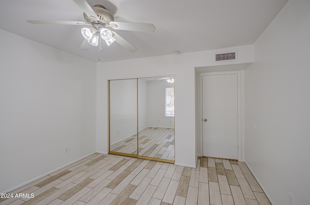 unfurnished bedroom featuring ceiling fan, light wood-type flooring, and a closet