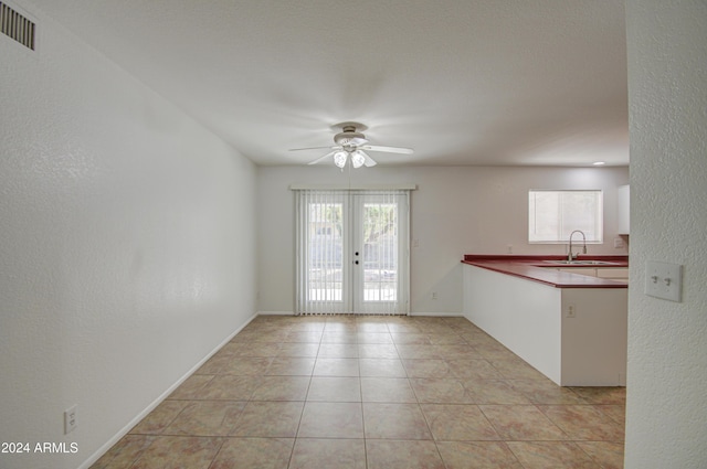 interior space with ceiling fan, french doors, light tile patterned floors, and sink