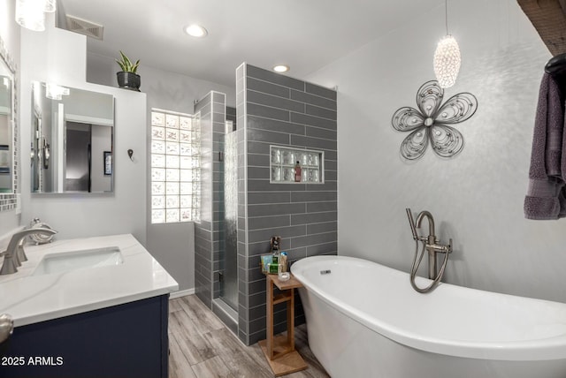 bathroom with wood finished floors, a stall shower, vanity, recessed lighting, and a freestanding tub