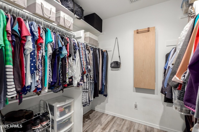 walk in closet with wood finished floors