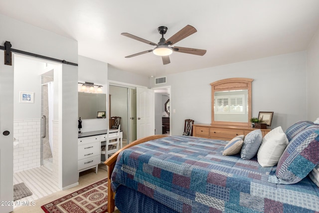 bedroom with a closet, ensuite bath, a ceiling fan, and a barn door
