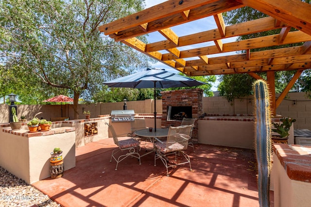 view of patio featuring an outdoor brick fireplace, area for grilling, a fenced backyard, and grilling area