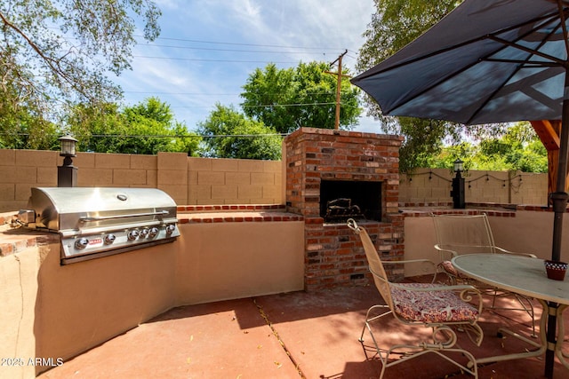 view of patio featuring an outdoor kitchen, area for grilling, an outdoor brick fireplace, fence, and outdoor dining area