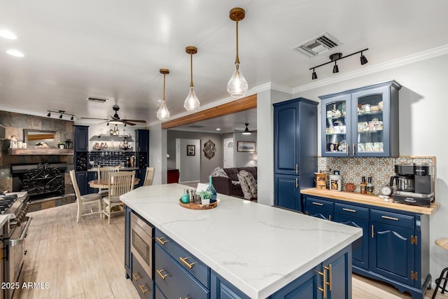 kitchen featuring blue cabinetry, a ceiling fan, open floor plan, appliances with stainless steel finishes, and crown molding