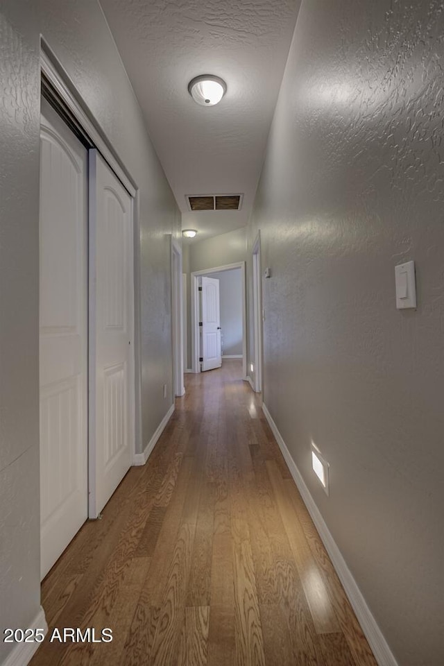 hall featuring wood-type flooring and a textured ceiling