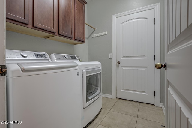 clothes washing area with cabinets, independent washer and dryer, and light tile patterned floors