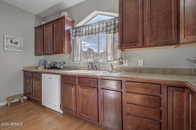 kitchen featuring tile counters, dishwasher, light hardwood / wood-style floors, and sink