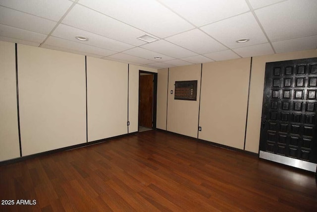 empty room featuring dark wood-type flooring and a drop ceiling