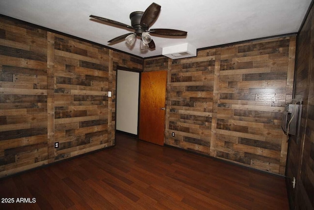 spare room featuring dark hardwood / wood-style floors, ceiling fan, and wood walls