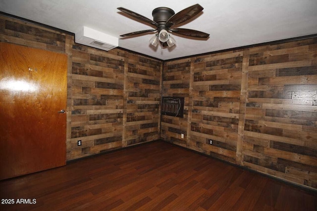 unfurnished room featuring dark hardwood / wood-style flooring, wooden walls, and ceiling fan