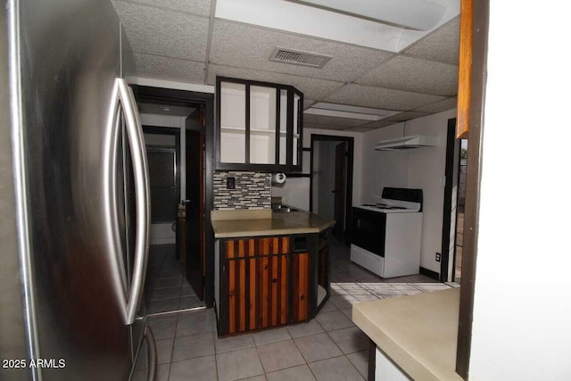 kitchen featuring stainless steel fridge, backsplash, light tile patterned floors, a drop ceiling, and electric stove