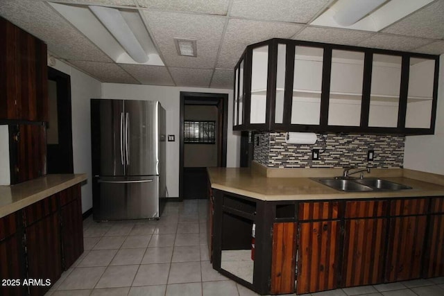 kitchen featuring sink, stainless steel fridge, decorative backsplash, light tile patterned floors, and dark brown cabinetry