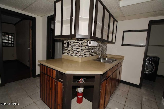 kitchen with light tile patterned flooring, sink, washer / clothes dryer, decorative backsplash, and a drop ceiling