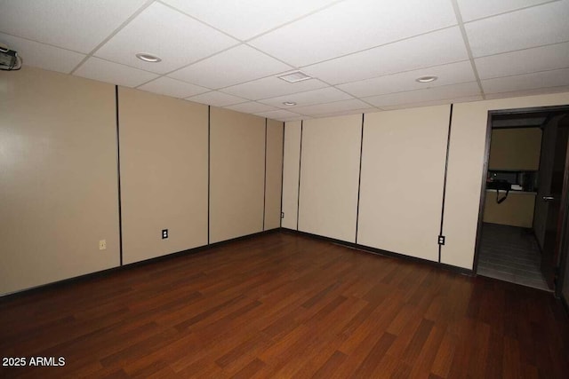 basement featuring dark wood-type flooring and a paneled ceiling