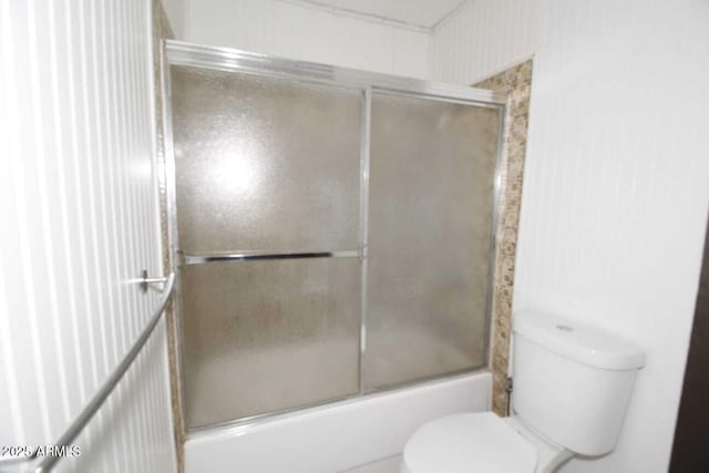 bathroom with enclosed tub / shower combo and toilet