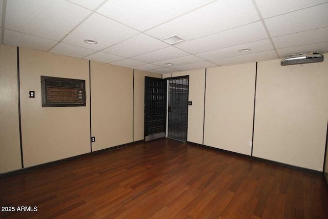 spare room with a drop ceiling and dark hardwood / wood-style floors