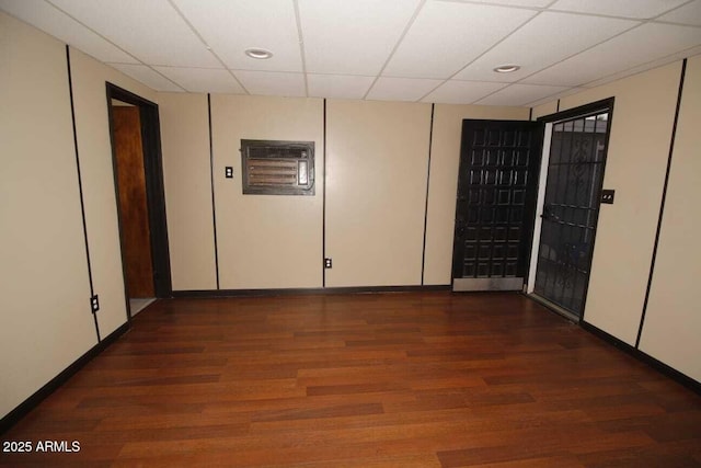 empty room featuring a paneled ceiling and dark hardwood / wood-style flooring