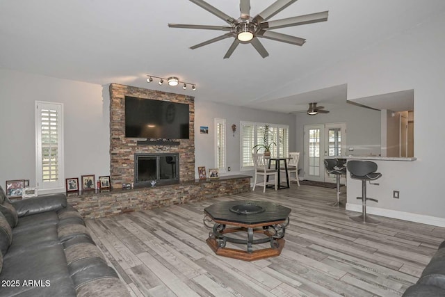 living room with plenty of natural light, french doors, a fireplace, and wood finished floors