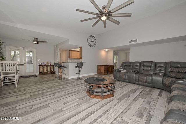 living room with baseboards, light wood-type flooring, visible vents, and a ceiling fan