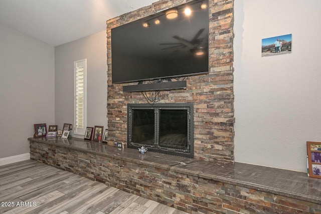 living room featuring a fireplace, wood finished floors, and baseboards