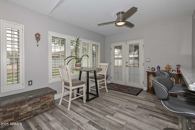 dining area featuring french doors, wood finished floors, a ceiling fan, and baseboards