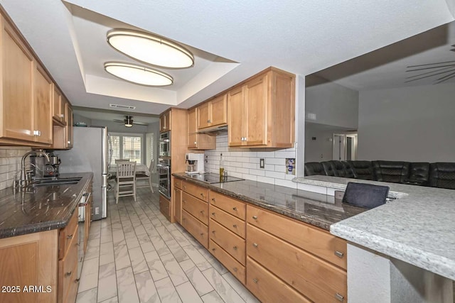 kitchen featuring tasteful backsplash, a raised ceiling, marble finish floor, black electric cooktop, and a sink