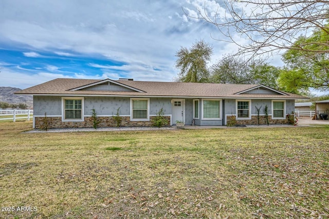 ranch-style house featuring stone siding, a front yard, fence, and stucco siding