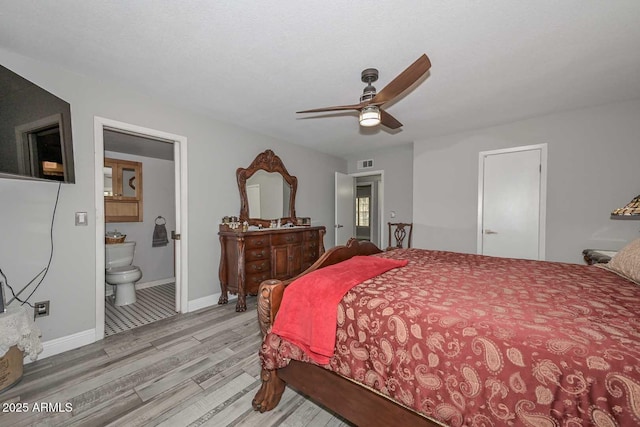 bedroom featuring baseboards, visible vents, a ceiling fan, wood finished floors, and ensuite bathroom