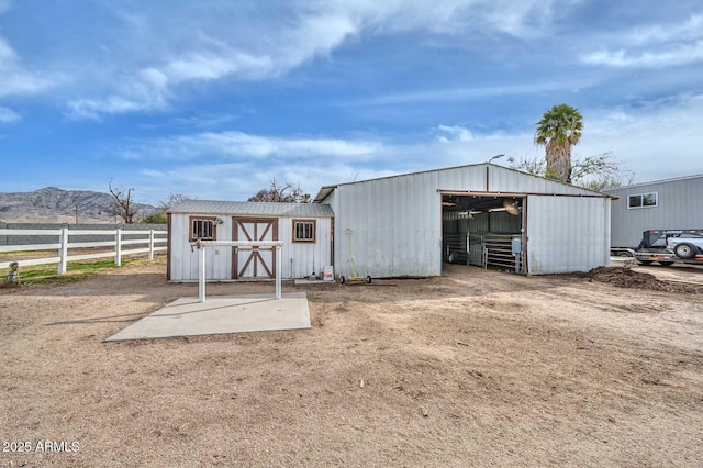 view of outdoor structure featuring an outbuilding, driveway, fence, and a mountain view