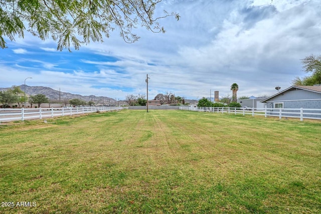 view of yard with fence, a mountain view, and a rural view