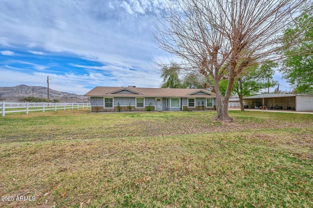 ranch-style house with stone siding, a mountain view, fence, and a front lawn