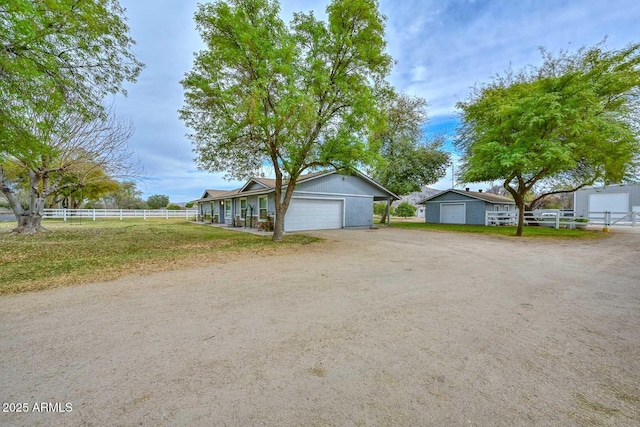 view of front of house featuring an attached garage, dirt driveway, and fence